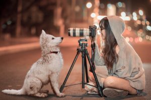 三脚で犬を撮影する様子の女の子の画像
